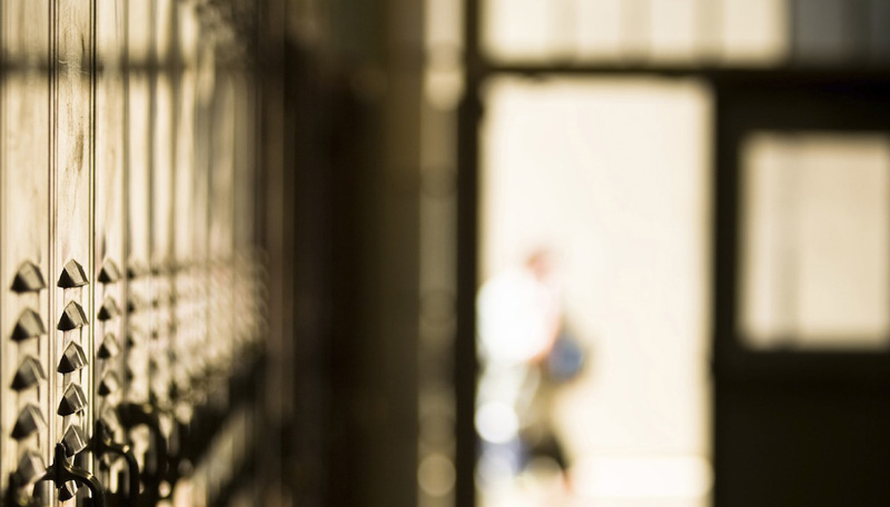 blurred image of lockers with student through door in hallway