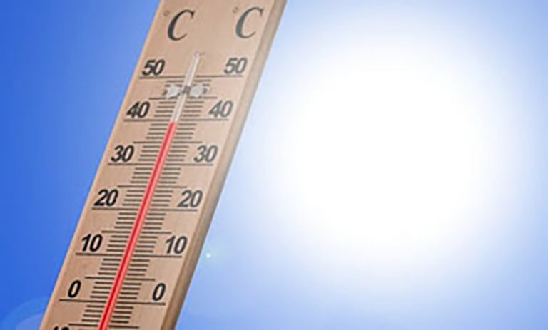 thermometer with blue sky and glare from sun in background