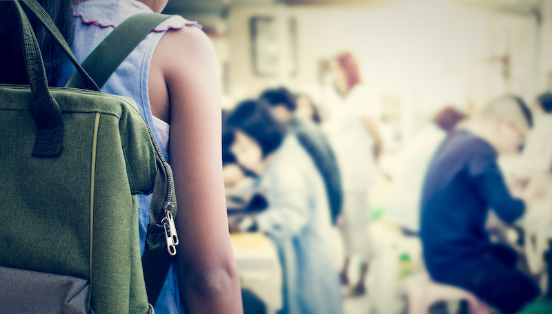 Girl with backpack entering to the classroom,