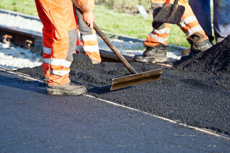 workers spreading ashphalt during road construction